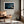 Matted desert dune print in a light wood frame above a leather lounge chair.
