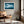 Blue Mirror mountain lake print in a light wood frame above a leather chair.