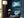 Framed blue mountain lake artwork on a dark blue wall beside a floor lamp and armchair.