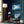 Framed blue mountain lake artwork on a dark blue wall beside a floor lamp and armchair.