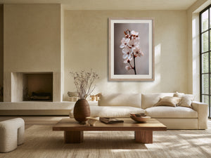Light wood-framed cherry blossom print above a cream sofa in a sunlit living area.