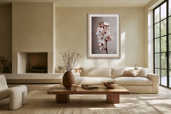 Light wood-framed cherry blossom print above a cream sofa in a sunlit living area.