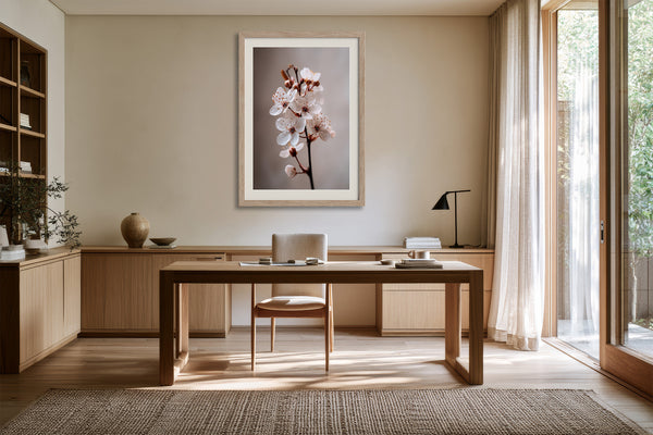 Light wood-framed cherry blossom print displayed above a wooden desk and chair.