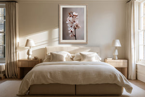 Light wood-framed cherry blossom print centered above a bed with cream bedding.