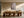 Light wood-framed cherry blossom print above a long wooden dining table and sculptural chairs.