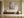 Light wood-framed cherry blossom print above a wooden bench beside a large ceramic vessel.