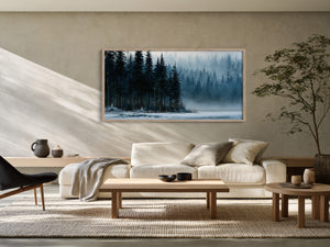 Framed winter forest and frozen lake artwork above a cream sofa in a sunlit living room.