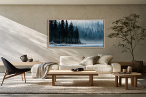 Framed winter forest and frozen lake artwork above a cream sofa in a sunlit living room.