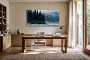 Framed winter forest artwork above a wooden desk with shelves and floor-to-ceiling windows.