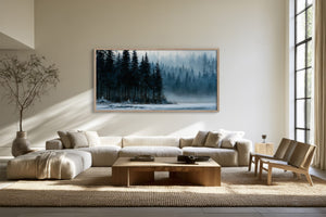 Framed evergreen forest and frozen lake artwork above a sectional sofa and wood coffee table.