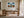 Framed stormy mountain ridge artwork displayed above a wooden desk beside tall windows.