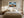 Framed stormy mountain artwork centered above a bed with cream bedding and bedside lamps.