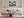 Framed stormy mountain ridge artwork displayed above a white sofa with blue cushions.