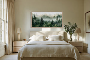 Framed misty pine forest watercolor above a neatly made bed between two wooden nightstands.