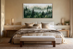 Framed misty pine forest watercolor above an upholstered bed with layered neutral bedding and bench.