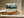 Framed misty pine forest watercolor above a long wooden sideboard beside full-length curtains.