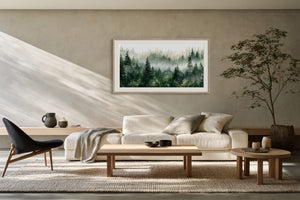 Framed misty pine forest watercolor above a cream sofa with wooden tables and a dark lounge chair.