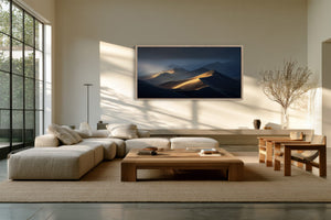 Framed desert dune artwork above a cream sectional sofa and wood coffee table.