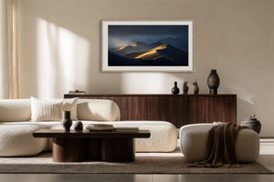 White-framed dune artwork above a dark wood sideboard in a neutral seating area.