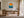 Framed golden sun and teal wave illustration displayed above a wooden desk.