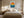 Framed sun and ocean illustration centered above a bed with cream bedding.