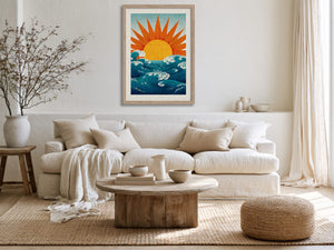Framed sun and ocean illustration above a cream sofa with neutral cushions.