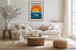 Framed sun and ocean illustration above a cream sofa with neutral cushions.