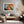 Light wood-framed abstract hare print above a wooden bench in a rustic sunlit setting.