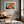 Light-framed abstract hare print above a tan leather lounge chair by a window.
