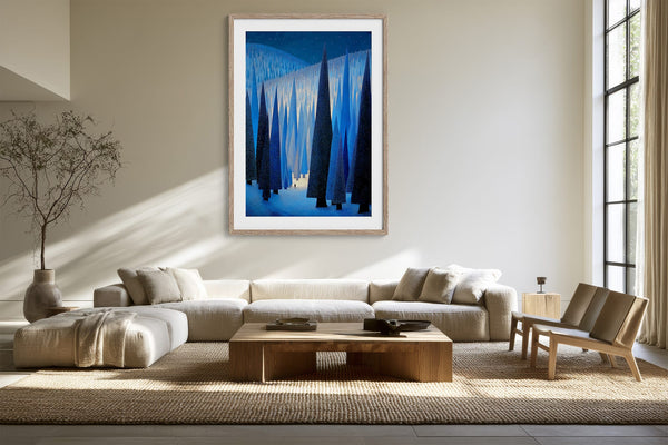 White-framed forest artwork centered above a cream sectional sofa in a sunlit living area.