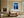 White-framed blue forest artwork above a cream sofa beside large grid windows.