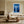White-framed blue forest artwork above a cream sofa beside large grid windows.