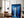 Large black-framed blue forest artwork leaning beside a brown armchair and floor lamp.