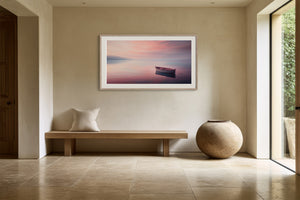 White-framed rowboat artwork above a wooden bench beside a large ceramic vase.