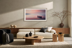 White-framed rowboat artwork above a cream sofa and low wooden coffee table.