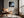 Framed misty shoreline artwork beside a leather lounge chair and sunlit window.