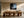 Framed pine-lined misty beach artwork above a long wooden dining table.