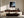 Framed misty shoreline artwork above a dark wood credenza and curved sofa.