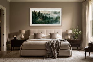 Framed misty conifer forest artwork displayed above a bed between two bedside tables.