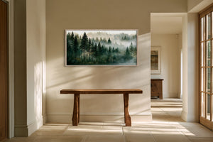 Framed misty forest artwork above a rustic wooden console in a sunlit hallway.