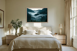 Light wood-framed misty conifer forest artwork centered above a bed between two nightstands.