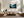 Light wood-framed misty forest artwork above a cream sectional sofa and low wooden coffee table.