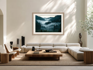 Light wood-framed misty forest artwork above a cream sectional sofa and low wooden coffee table.