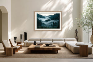 Light wood-framed misty forest artwork above a cream sectional sofa and low wooden coffee table.