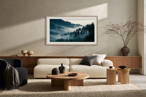 Framed forest landscape above a low cream sofa and wooden console.