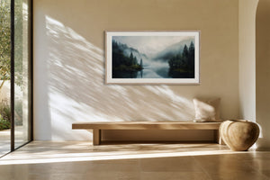 White-framed misty conifer lake artwork above a low wooden bench.