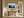 Light wood-framed misty pine forest artwork above a rustic wooden console in a sunlit hallway.