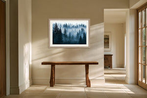 Light wood-framed misty pine forest artwork above a rustic wooden console in a sunlit hallway.