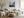 Framed misty mountain forest artwork above a cream sofa, with a wood coffee table and round ottoman.