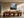 Framed misty mountain forest artwork above a long wooden dining table with sculptural chairs.